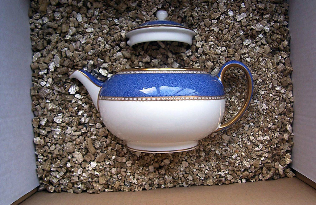 Porcelain teapot being packed in vermiculite prior to shipment 